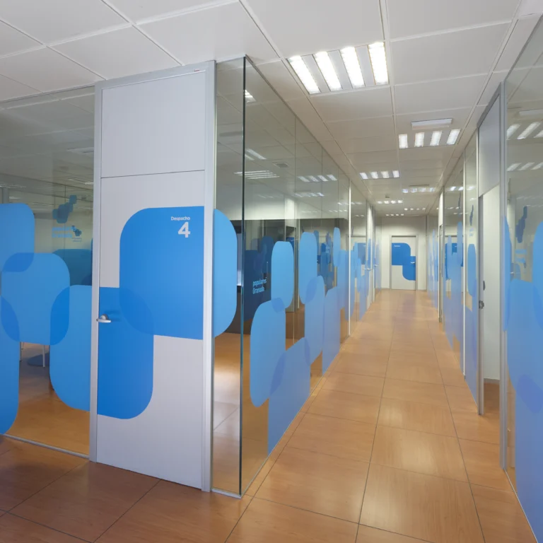 Pasillo de oficina con mamparas de vidrio de suelo a techo Mamper Glass y despachos con vinilo decorativo